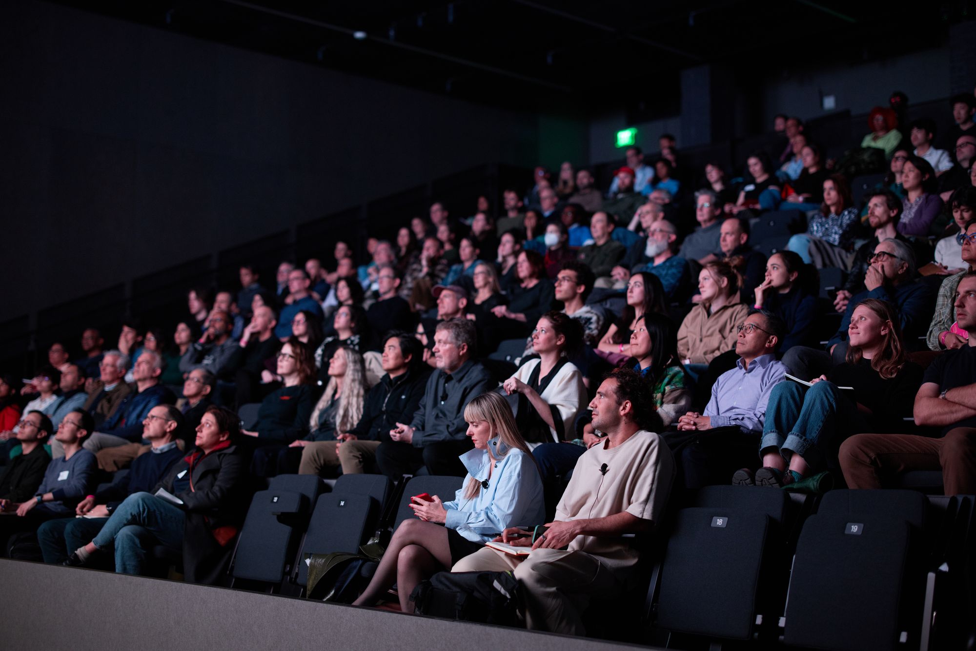 Looking up at the attendees as the screening bathes their faces in blue light.